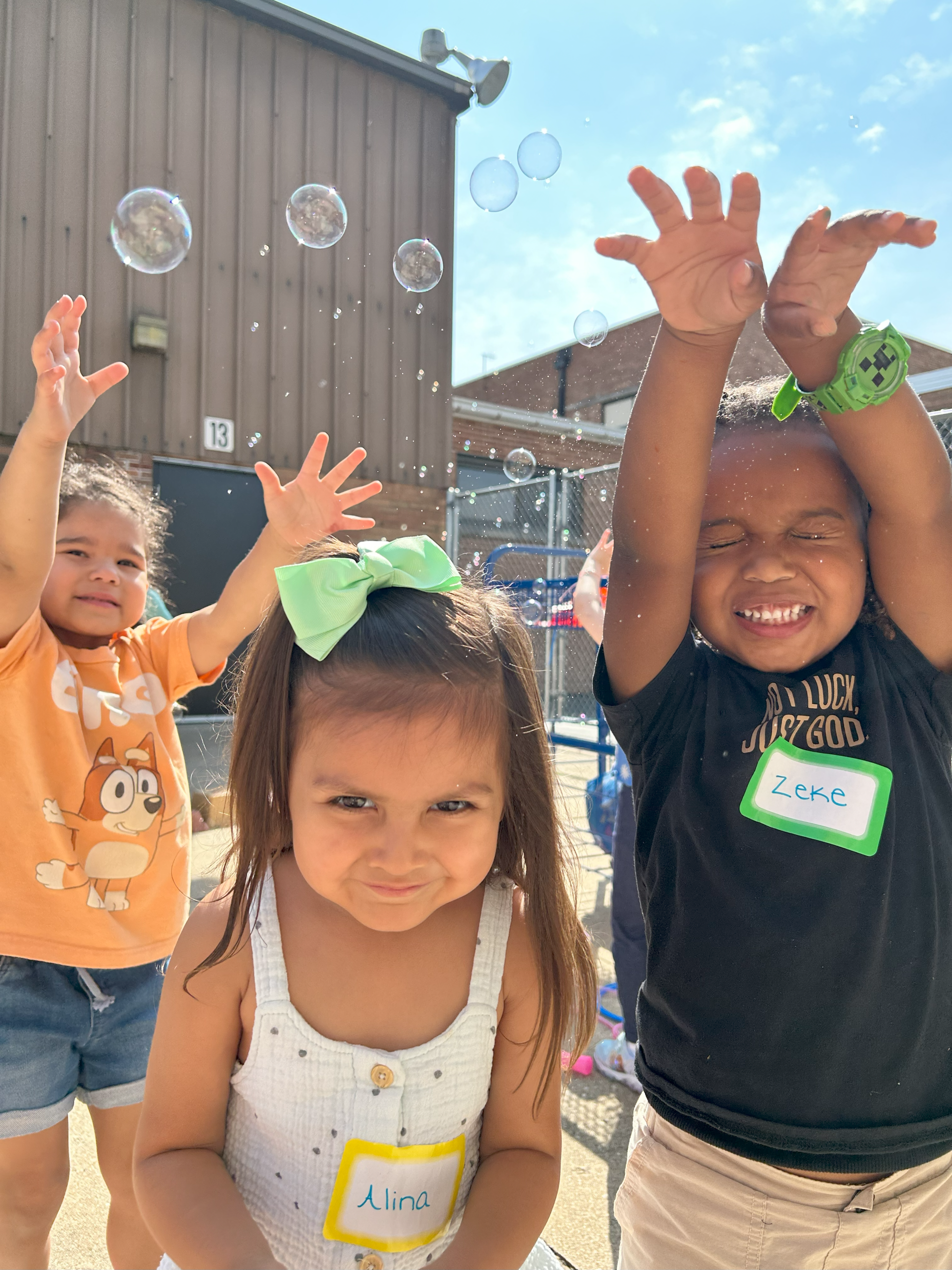 Preschool students playing outside with bubbles. 