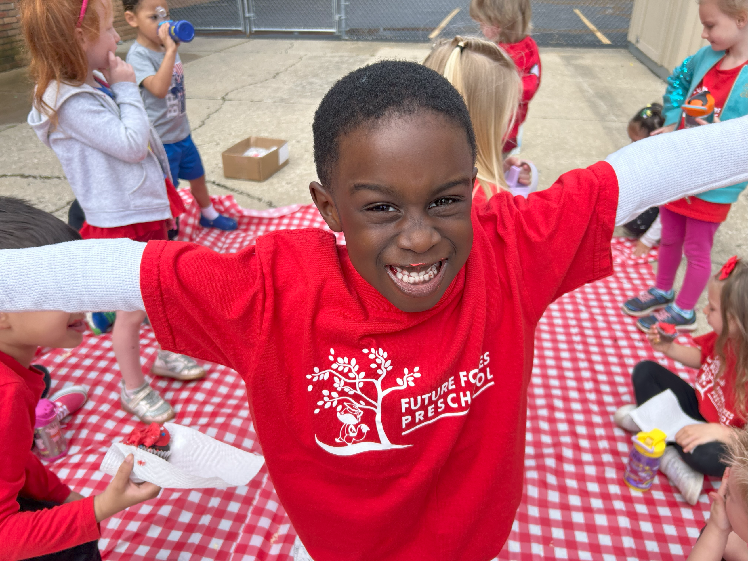 A boy wearing a red shirt with the Preschool logo on it. 